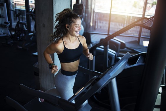 Top view of smiling woman exercising and training in the gym on treadmill running machine. Healthy lifestyle and positive people.